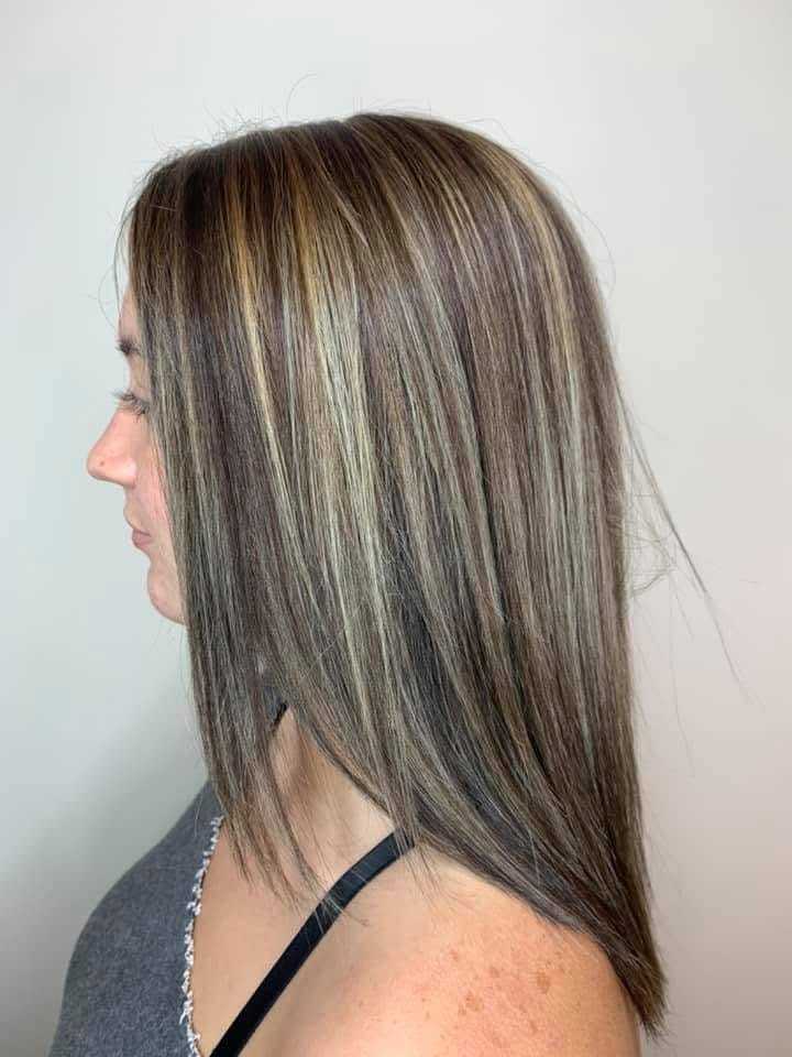 Woman with straight, layered hair featuring blonde highlights, side profile view.