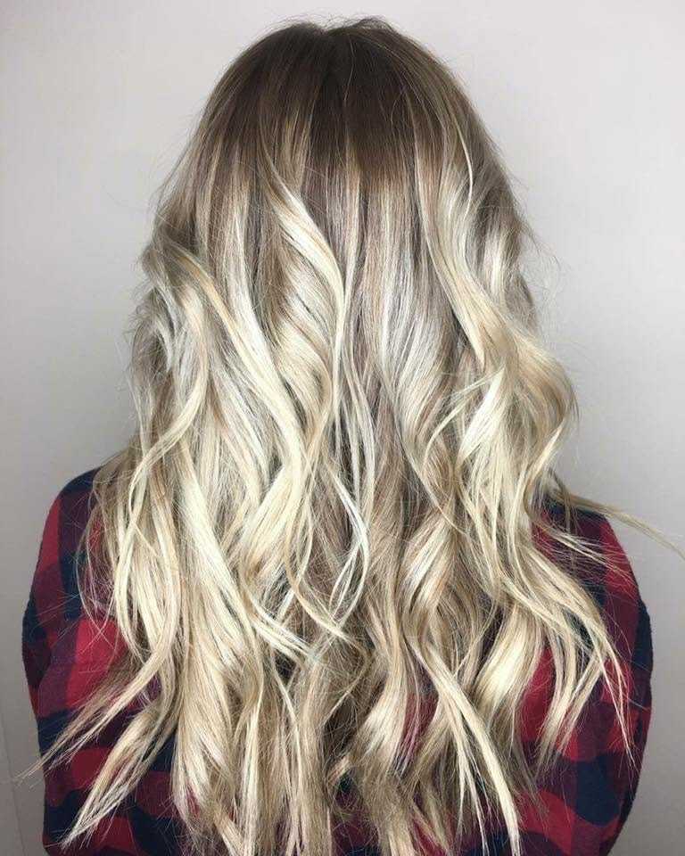 Blonde wavy hair on a person in a red and blue plaid shirt, viewed from the back.
