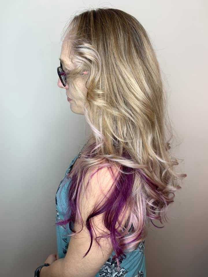 Woman with long blonde hair and purple tips, wearing glasses, in profile view.