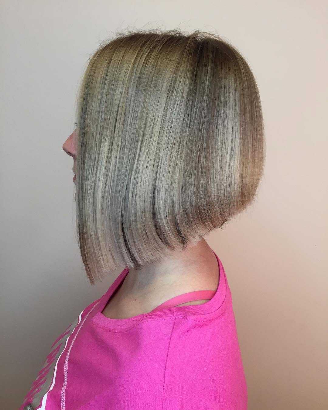 Blonde bob haircut on woman in pink shirt, side view.