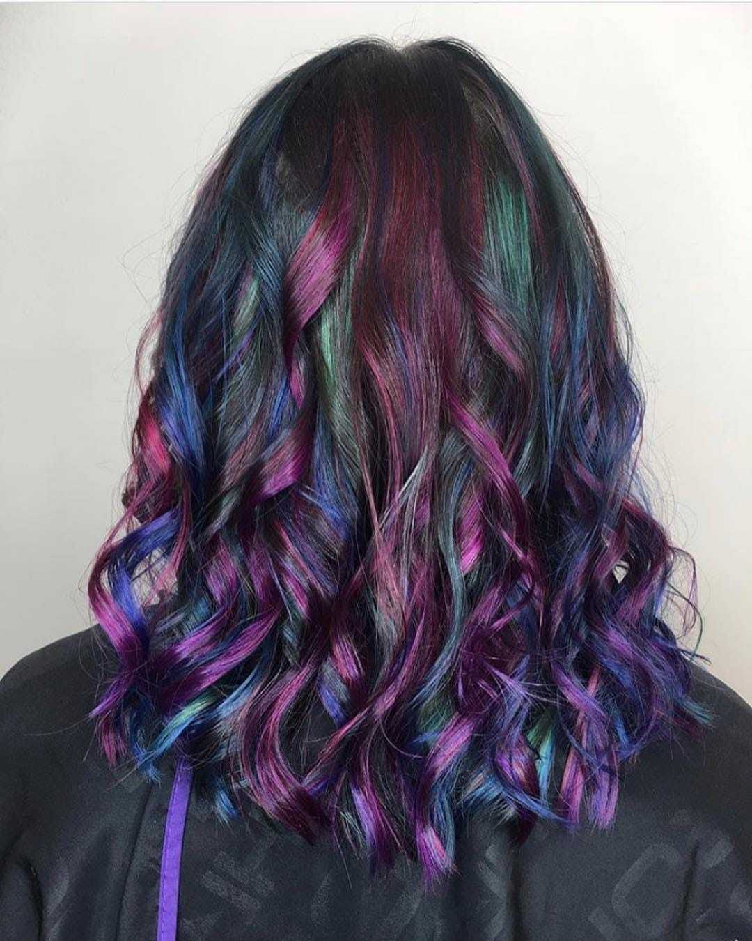 Curly hair dyed in vibrant purple, blue, and green hues.