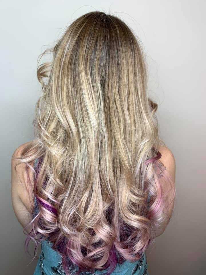 Blonde hair with pink highlights cascading in curls down a woman's back.